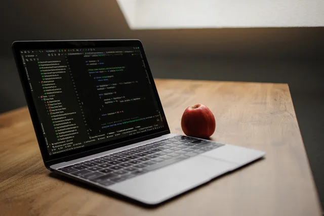 Open laptop displaying code next to a red apple on a wooden desk. Web design agencies 2027 trends: five England signals to monitor