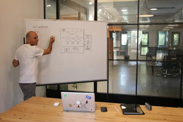 Side view of middle aged male leader in white t shirt writing on whiteboard during presentation in modern office space with glass walls. KOTA Creative Ltd agency review: claims, evidence gaps and a hold verdict