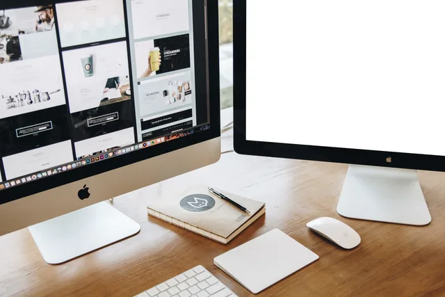 High-angle view of a stylish work desk featuring dual monitors, keyboard, mouse, and modern accessories. Web design agencies in England: checking who is the contracting party