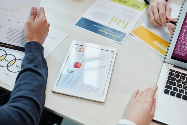Top view of a business meeting table with digital devices and financial documents, showing collaboration. Web design agencies launch review: evidence checklist