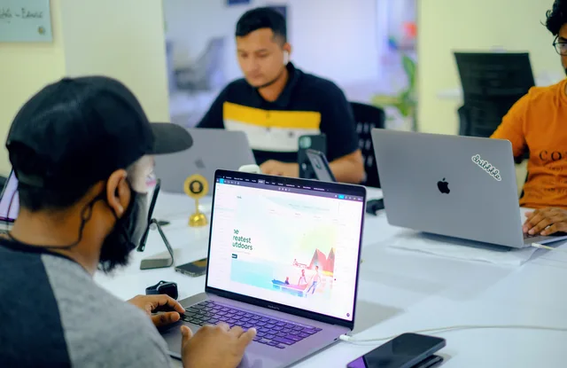 Business colleagues collaborating in an office setting with laptops and electronics. Web design agencies market entry checklist: nine gates