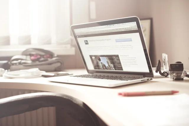 A clean and bright workspace featuring a laptop open on a wooden desk, highlighting a typical tech environment. Three scenarios for England's web agencies and what would disprove each