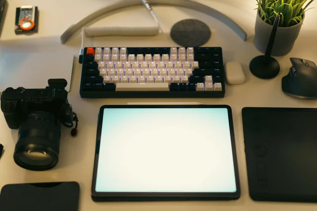 A stylish desk setup featuring a digital tablet, keyboard, camera, and plant, ideal for creative work. Seven England web agencies named, and identity checks to run before reputation
