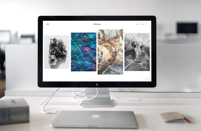 A contemporary office desk setup featuring a sleek computer monitor displaying abstract artwork. Web design agencies risk scenarios: five delivery risks