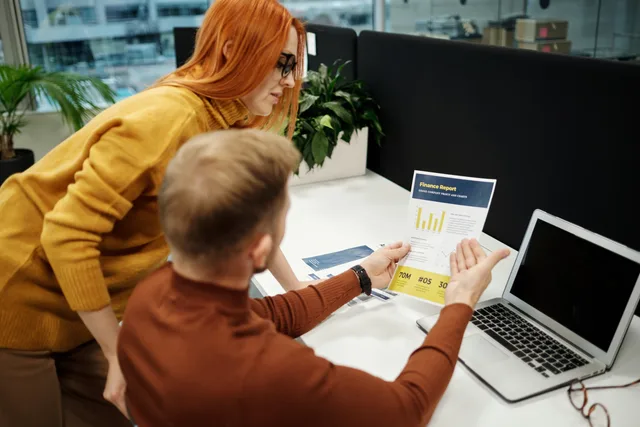 Two colleagues analyzing a financial report in a modern office setting with a laptop. Web design agencies strategy: an evidence-led brief